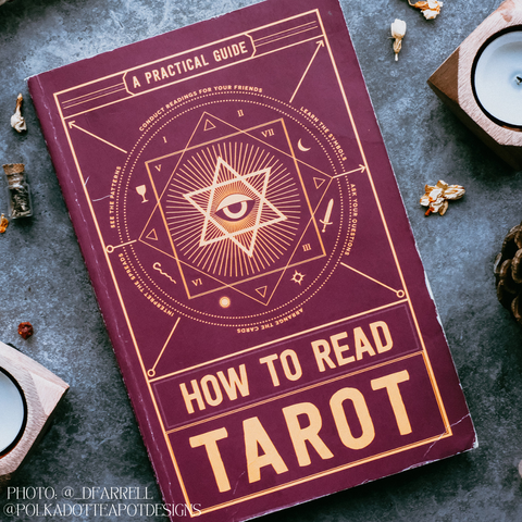 A photo of a book cover titled “How to Read Tarot: A Practical Guide”. The book is maroon in colour with gold lettering and illustrations.