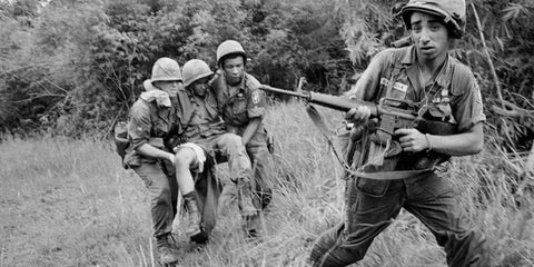 M16 rifle causing casualties in war; photo of two soldiers carrying a wounded soldier