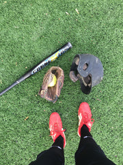 photo of fastpitch field with bat, glove, helmet, and red cleats