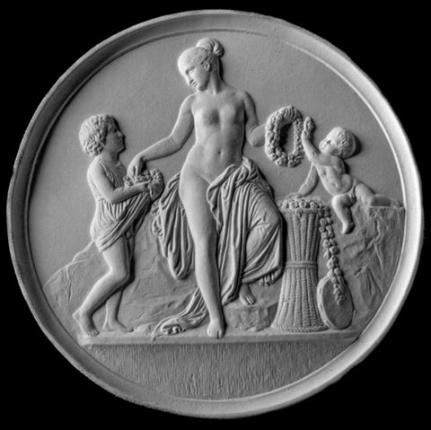 photo with black background of plaster cast relief sculpture of mostly nude female figure with two children and flowers and wreaths