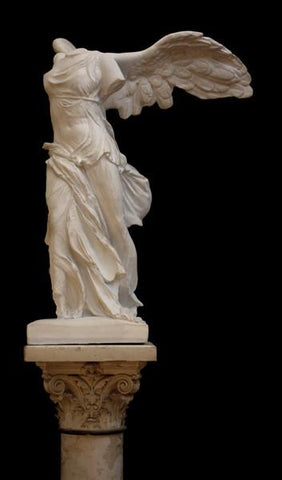 photo of plaster cast sculpture of winged, headless female figure with flowing drapery on top of an ornate, floral pedestal on a black background