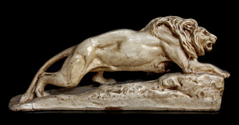 Photo of plaster cast of original Caproni sculpture of a small  lion crouching on a black background