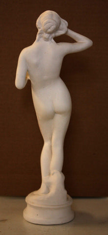 Photo of back view of plaster cast of female nude with dark background