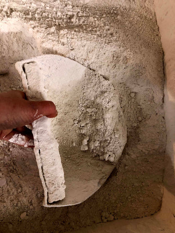 hand putting scoop into bucket of plaster in powder form