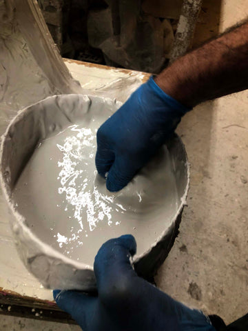 hands in blue gloves mixing plaster in a bucket