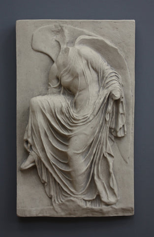 photo of cast of sculpture relief of robed figure, head now missing, reaching for her sandal in Stone Patina on a dark gray background