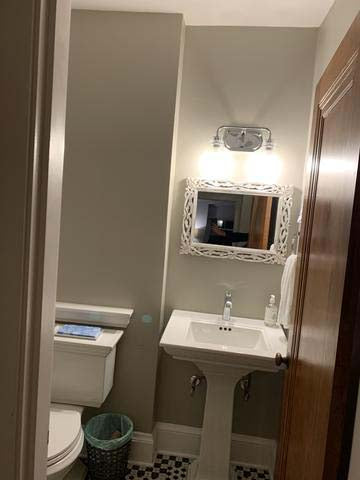 Small powder bathroom with grey walls, black and white floor tiles.