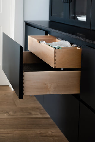 Black cabinet drawer pulled out to reveal drawer inside of drawer storage