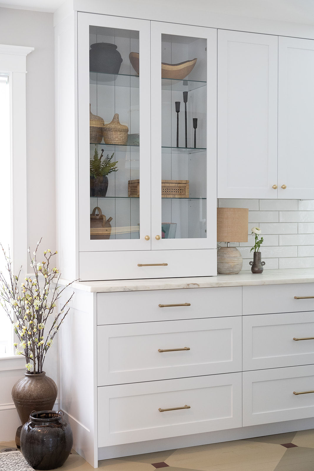 White kitchen with glass cabinets and small lamp under upper cabinets