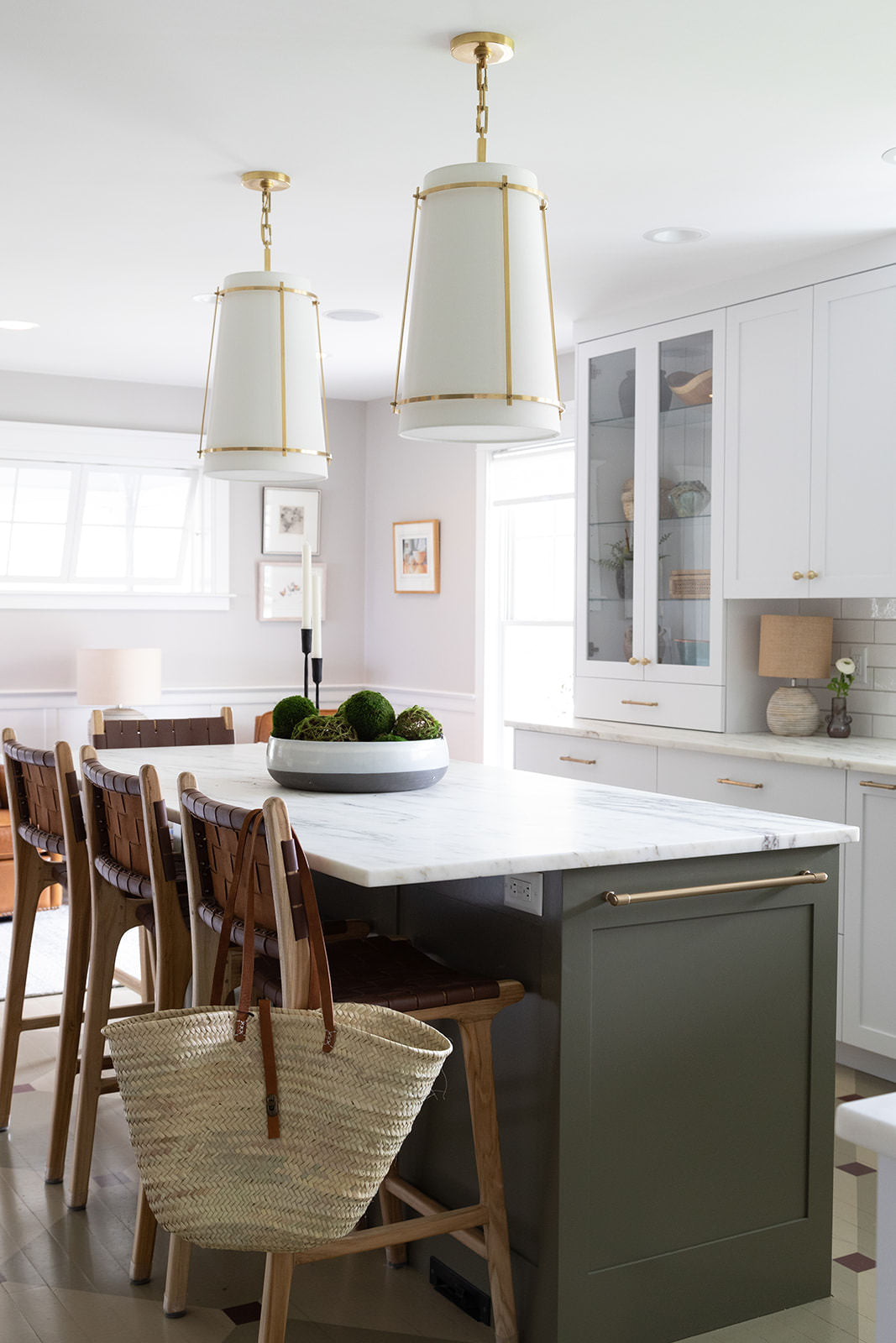 White kitchen with dark green kitchen island and white pendant lights