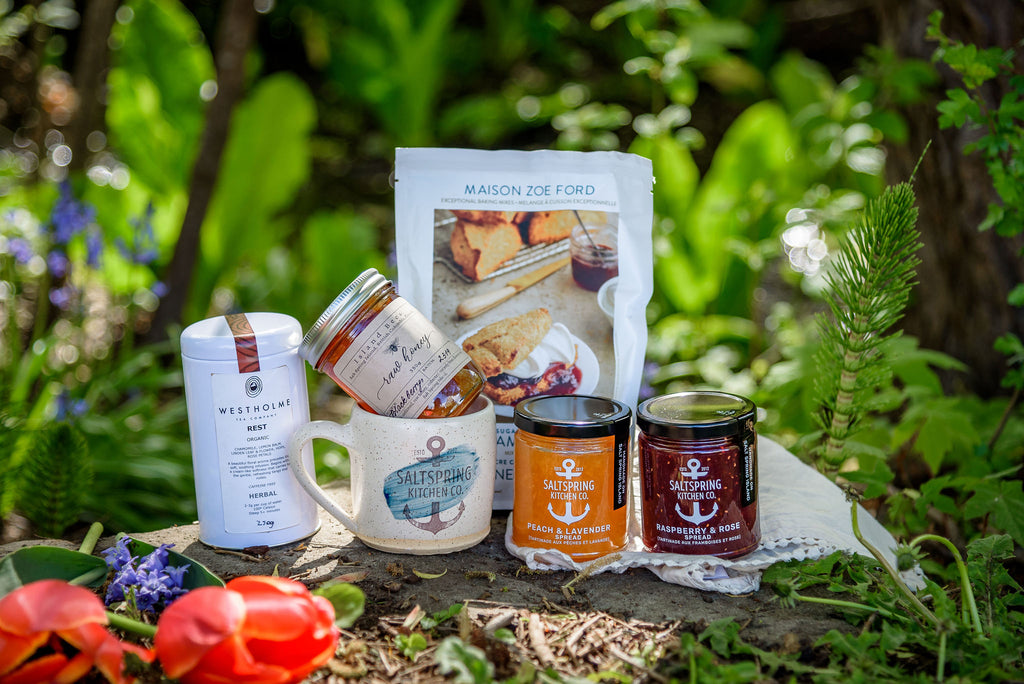 SaltSpring Kitchen Company Limited Edition Mother's Day Gift Box contents of preserves, honey, tea and ceramics on a blanket outside