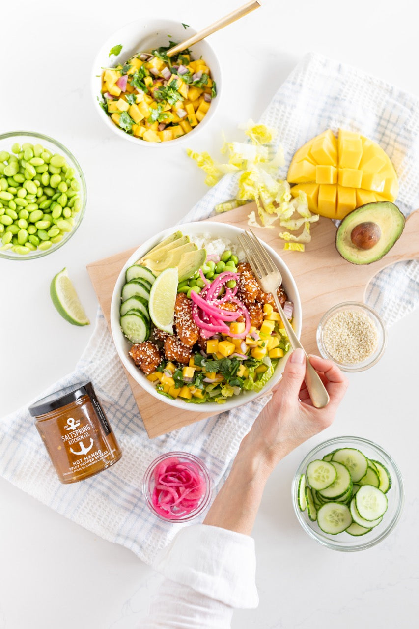 Tori Wesszer's Spicy Mango Rice Bowl on the counter with toppings and Hot Mango Spicy Pepper Spread