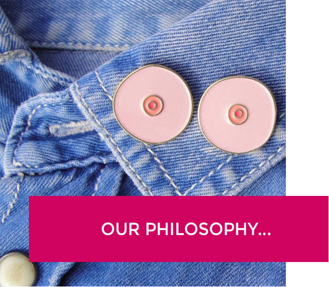 Boob pins on a jean jacket with a banner that says "our philosophy".