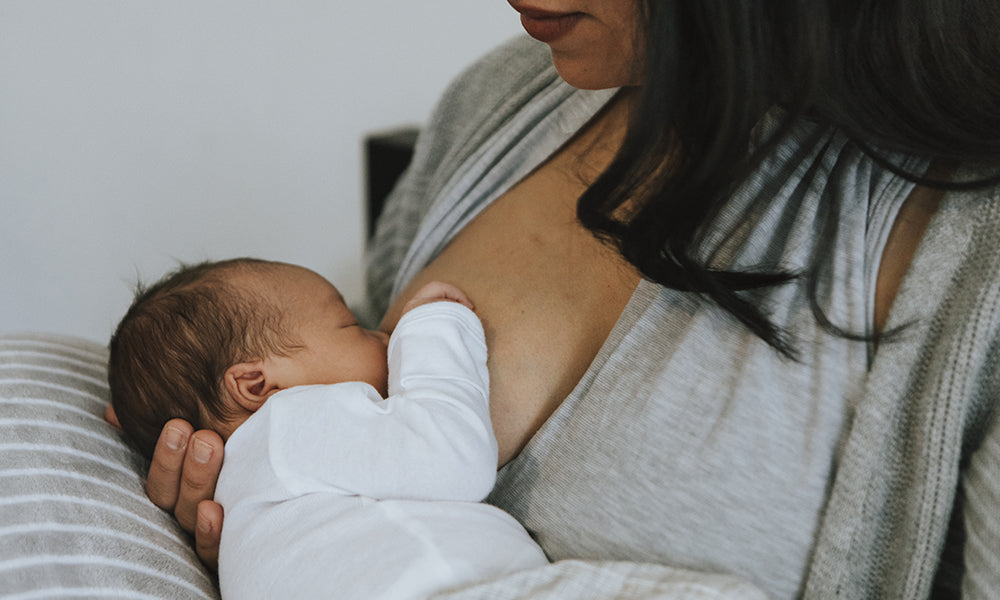 A woman holds a baby as she breasfeeds them