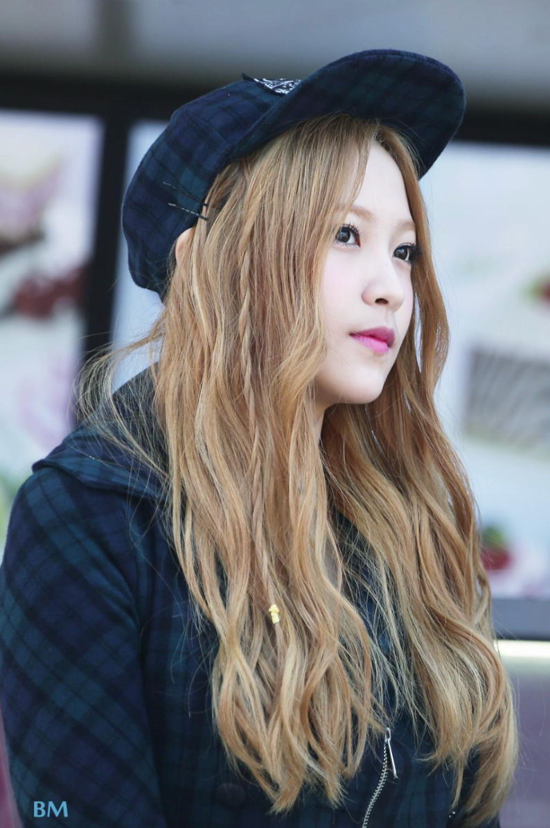 red velvet yeri long blond hair wearing a black jacket and hat in a public space