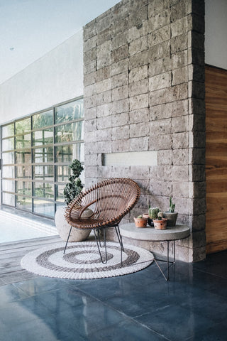 An interior space with a stone wall, house plants, large glass windows looking out to green space
