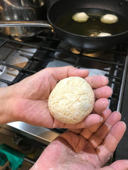 Sesame coated doughnut ball dough in palm of hand