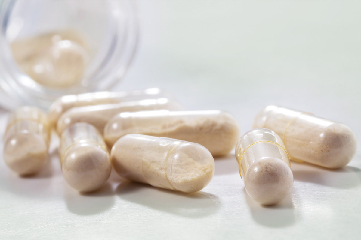 An glass bottle lays open exposing probiotics capsules to the light.