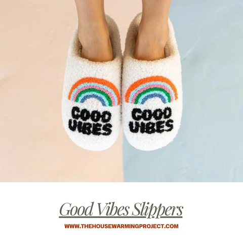 A pair of feet wearing Good vibes slippers.