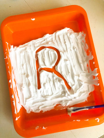 activity tray filled with shaving cream and an R written in the shaving cream