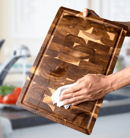 Acacia Cutting Board being cleaned by a wet cloth