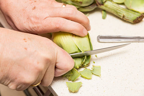 Trimming an artichoke involves removing the tough outer leaves and trimming the stem to reveal the tender heart