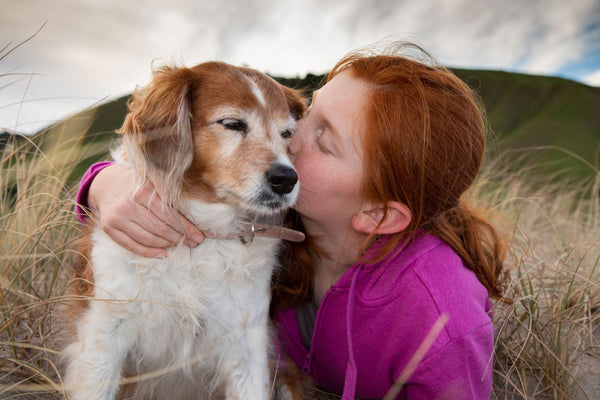 Girl kissing her dog on the head