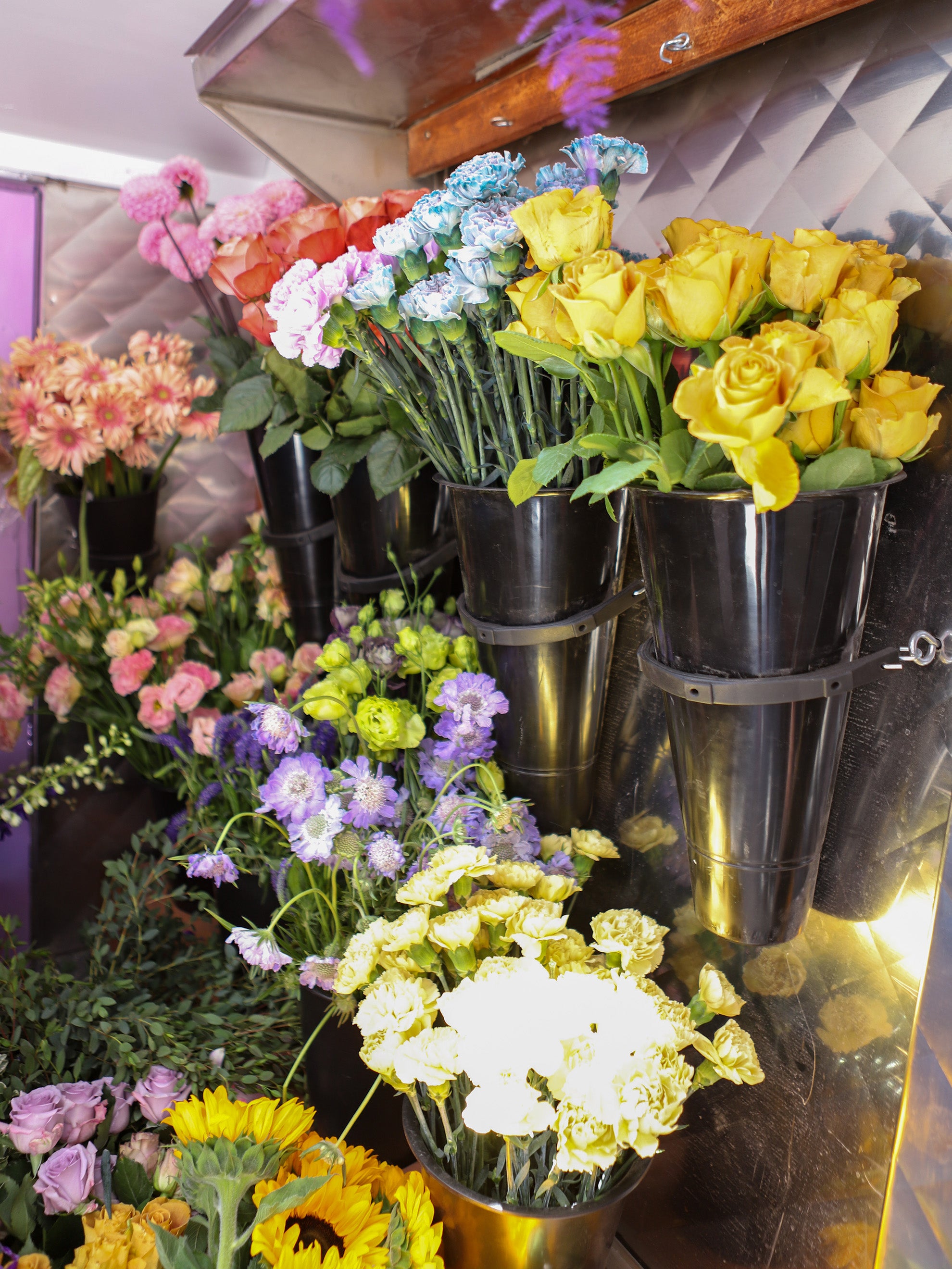 The inside of the truck that holds a variety of flowers in black holders