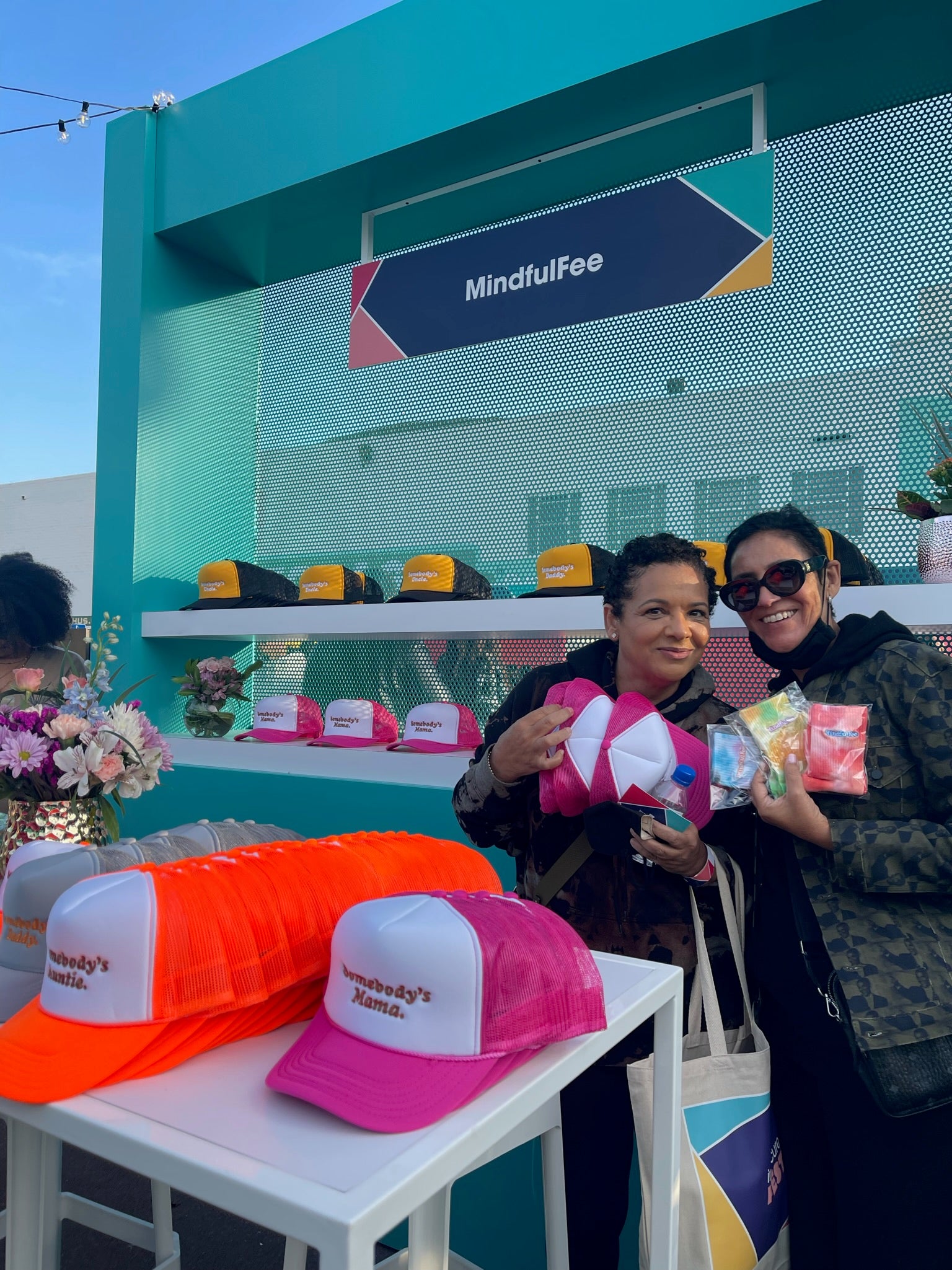 2 women holding MindfulFee hats at our booth