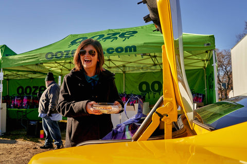 Brunette Girl holding an apple pie in front of an Ooze tent. 