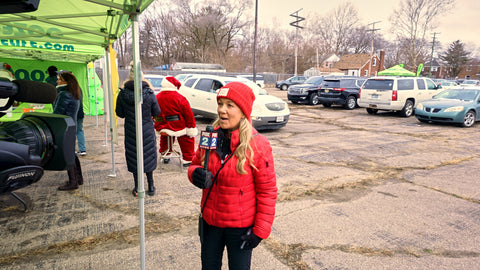 Blonde women with matching red hat and jacket talking into a microphone for local news station