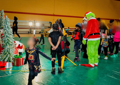 The gym at the Heilman Recreation Center in Detroit is filled with kids waiting in line to take a photo with the Grinch and Santa. All children's faces are blurred to protect their identities.