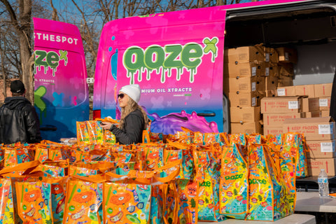 A sea of reusable Ooze bags is in front of the OozeX van filled with frozen turkeys at the Oozegiving food drive. 