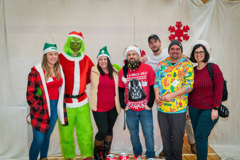 A group of Ooze employees are standing together with the Grinch at the Oozemas holiday party.