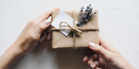Gift wrapped in brown paper and twine with lavender, held in two hands