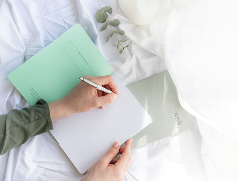 Girl writing on notebook pages looking down from above