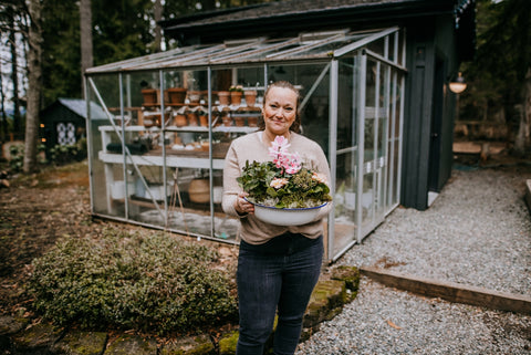 jess buttermore holding meaningful mother's day planter gift to mom cedar house living in front of greenhouse