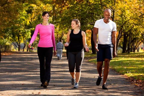 Two women and a man walking together outdoors.