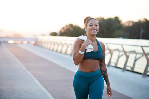 Woman wearing exercise clothes and walking along pathway near the water.