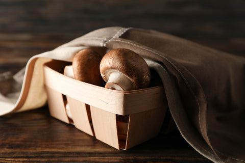 uncooked mushrooms in a basket covered by a cloth
