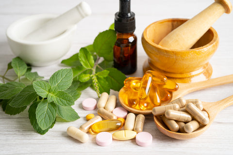 The image represents supplements. Vitamin pills on the counter and in wooden spoons.