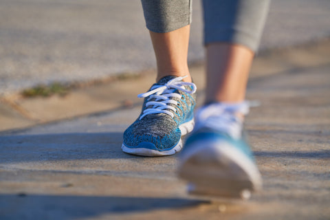 Photo of person's legs from the ankle down wearing sneakers while walking outside.