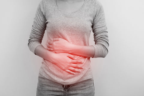 Woman standing her hands are touching her stomach which has a red glow around.