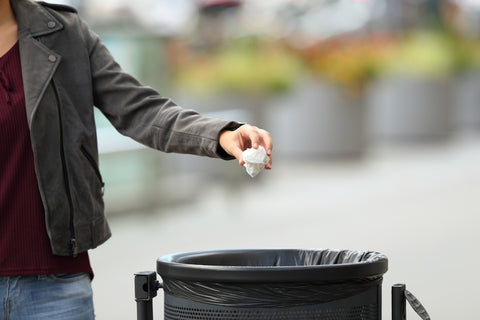 A man, who is outside, is dropping garbage into a bin.