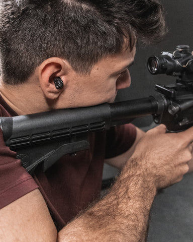 Man shooting rifle with tactical hearing device in ear