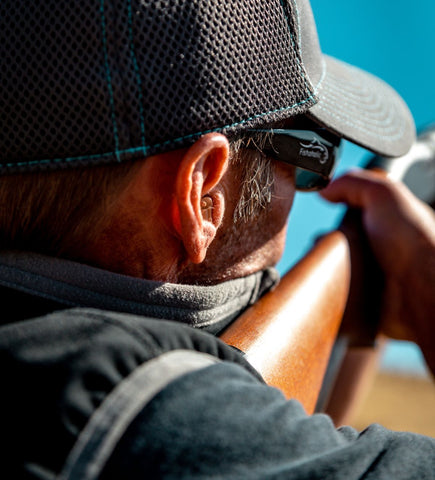Tactical Hearing earbud in man's ear while shooting a gun
