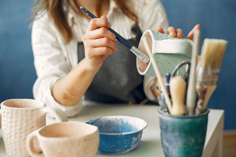 woman painting clay pot in pottery class