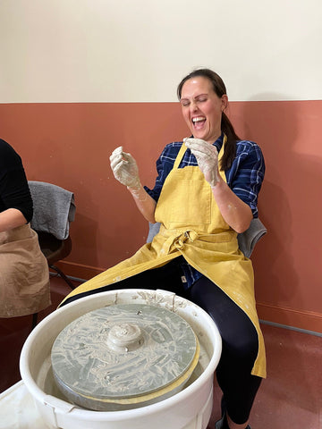 woman laughing sat at pottery wheel