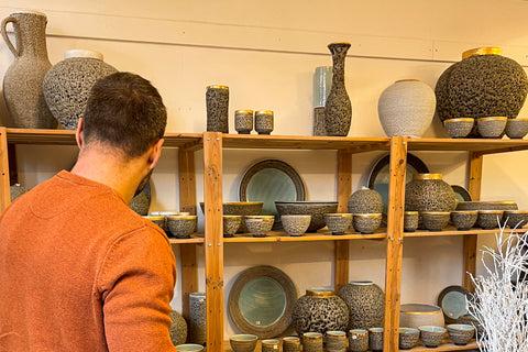 man standing in front of shelves of pottery