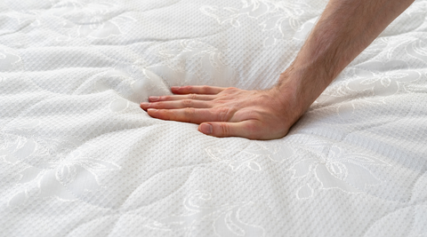 A memory foam mattress being tested by an elderly man.